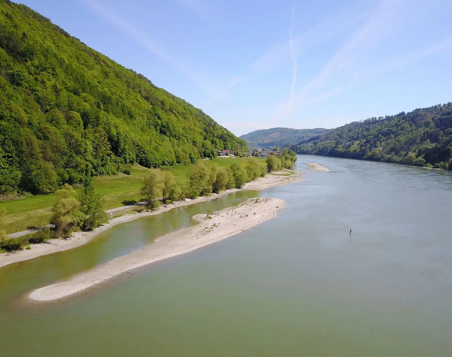 Ein Blick auf die Donau von oben. Rechts und links ist satt grüne Vegetation zu sehen. Im Fluss zeigt sich eine der neuen Kiesstrukturen, die in Zukunft als Fischlaichplätze dienen werden.